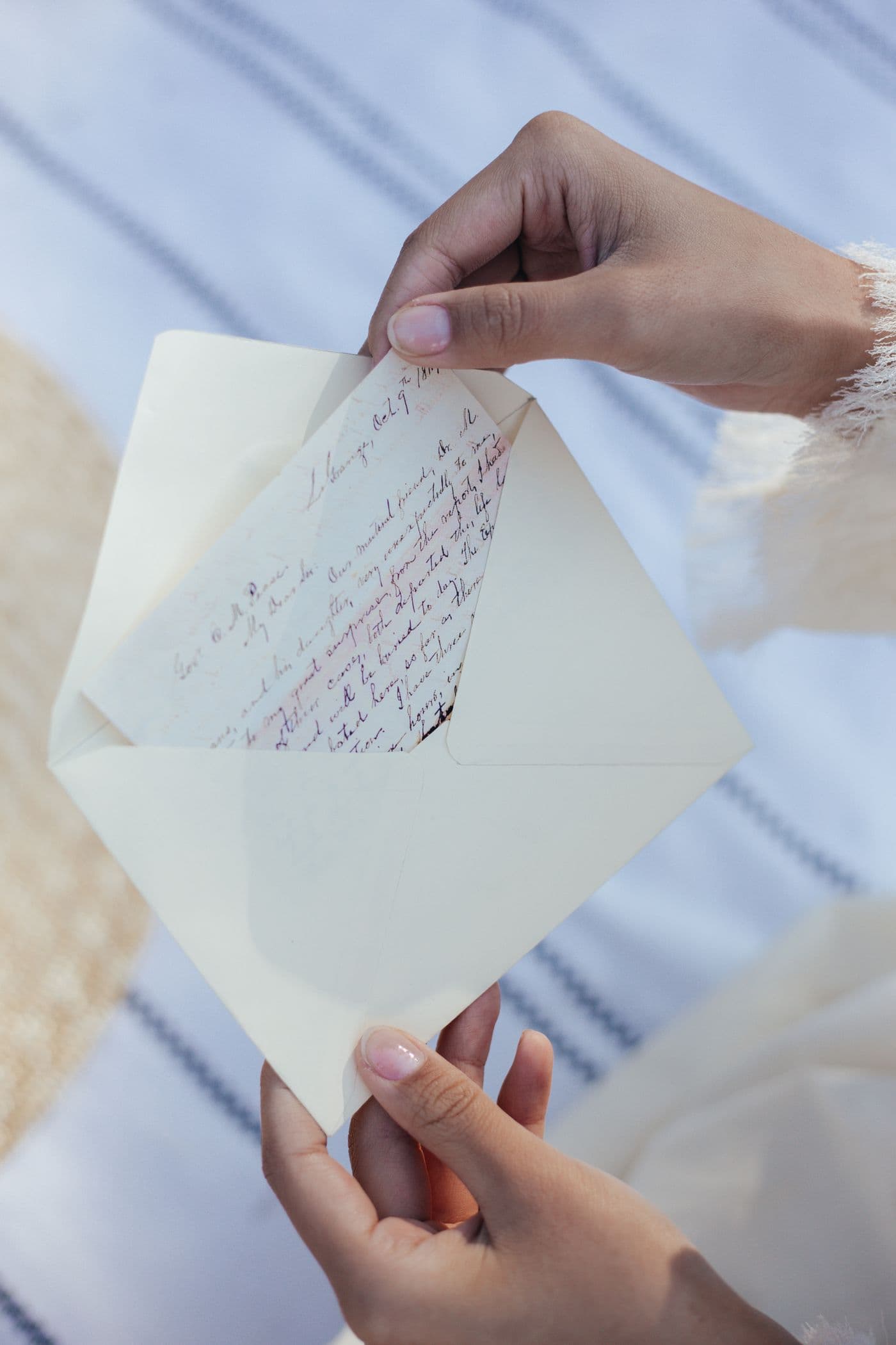A woman's hands drawing a handwritten 19th-century letter from its envelope.